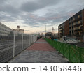 Apartment building and promenade under construction, illuminated by the setting sun. 143058446