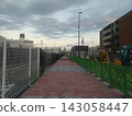 Apartment building and promenade under construction, illuminated by the setting sun. 143058447
