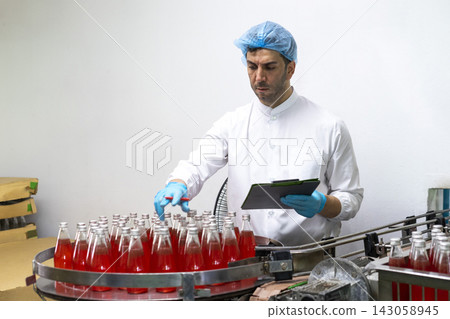 Male workers in factory checking products. Workers inspecting production line at drinks production factory. Male workers in factory checking products. Workers inspecting production line at drinks production factory. 143058945