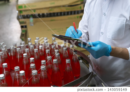 Close-up of worker hand in protective glove counting and checking drink bottle in bottle factory. 143059149