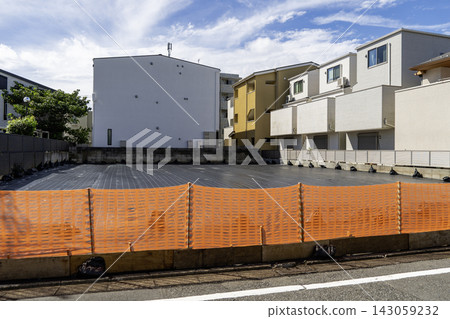 A construction site in a residential area surrounded by a safety fence, and the blue sky. A construction site in a residential area surrounded by a safety fence, and the blue sky. 143059232