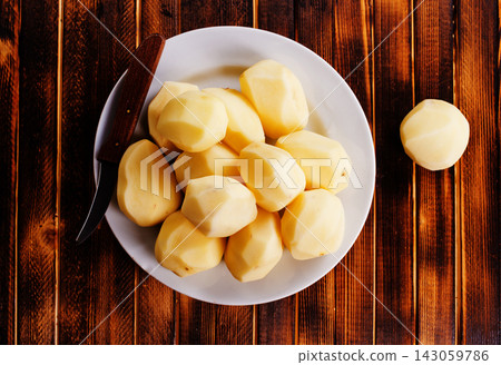 Plate with raw potatoes on wooden background Plate with raw potatoes on wooden background 143059786