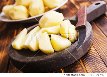 Plate with raw potatoes on wooden background Plate with raw potatoes on wooden background 143059792