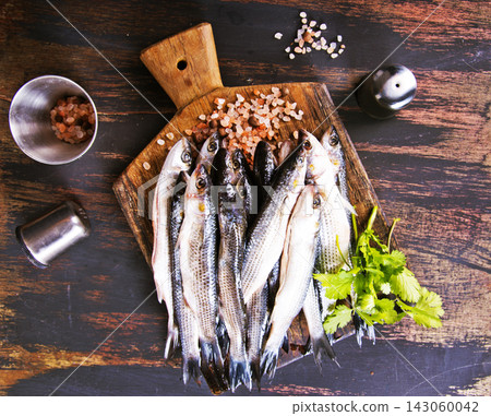 small fish for cooking on wooden board 143060042