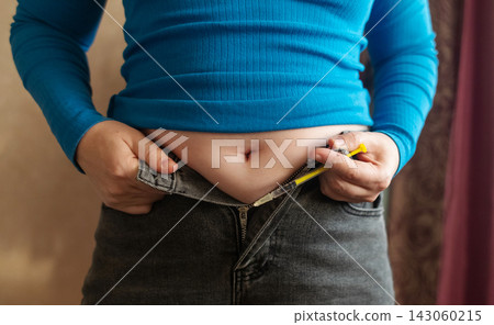 Woman receiving weight loss injections and fat dissolving injections into belly fat at home. Close up of stomach subcutaneous injection, lipolytic, fertility hormone, or insulin therapy. 143060215