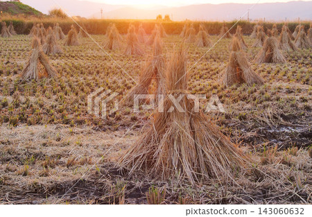 夕陽西下,群山環繞,稻田裡堆滿了稻草。 夕陽西下,群山環繞,稻田裡堆滿了稻草。 143060632