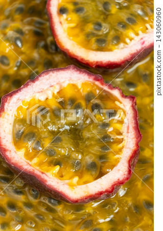 Halved passion fruit slices placed over juicy fruit pulp background Halved passion fruit slices placed over juicy fruit pulp background 143060960