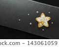 Beautiful handmade embroidered brooch,white and golden star with crystals,lying flat on the dark gray stone rectangular background, horizontal top view 143061059