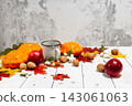 Bright autumn horizontal background with orange pumpkins and red apples, nuts, a cup of tea, green and yellow leaves, lying flat on the white desk wood wih empty place for your text, perspective view 143061063