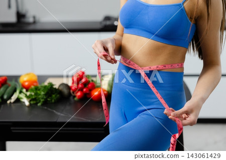 Woman measuring waist with tape for weight loss Woman measuring waist with tape for weight loss 143061429