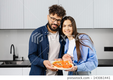 Happy couple preparing fresh homemade pizza in kitchen Happy couple preparing fresh homemade pizza in kitchen 143061441