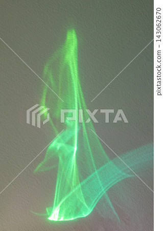 Green light projection forming an abstract glowing fabric-like shape on a textured wall Green light projection forming an abstract glowing fabric-like shape on a textured wall 143062670