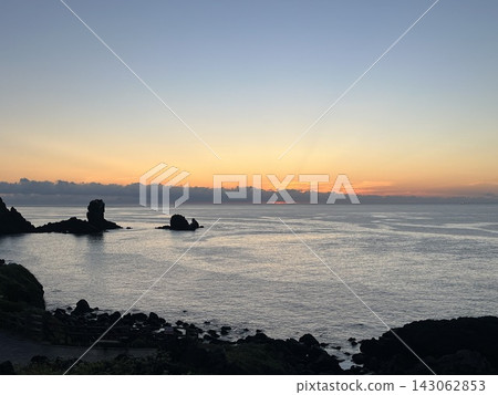 A volcanic sea stack silhouetted against the sunrise over Seongsan Mountain in Jeju. A volcanic sea stack silhouetted against the sunrise over Seongsan Mountain in Jeju. 143062853