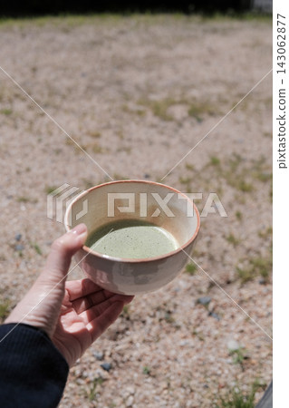 在戶外享用抹茶，手中拿著抹茶碗。 143062877