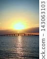 夕陽西下，大海泛著金色的光芒，一座大橋橫跨地平線。 143063103