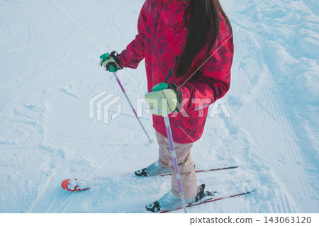 一名高中女生穿著滑雪板站在滑雪道上，她的雙腳清晰可見。 143063120