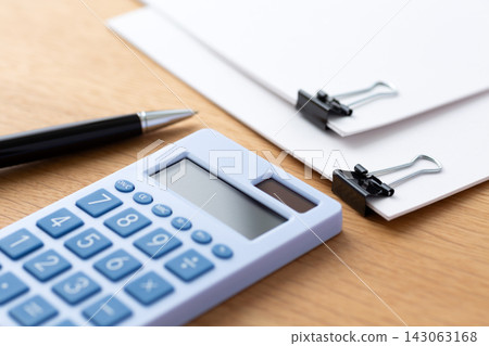 Business documents held together with a paper clip and a calculator Business documents held together with a paper clip and a calculator 143063168