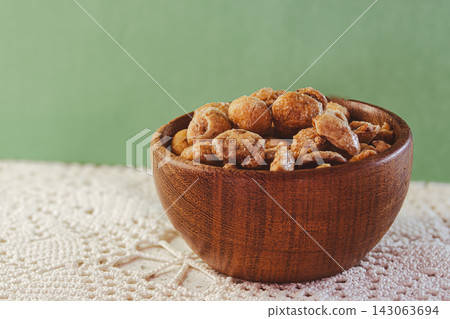 Glazed peanuts and almonds in a wooden bowl, a crunchy snack or sweet treat, a delicious mixture of nuts and caramel, isolated Glazed peanuts and almonds in a wooden bowl, a crunchy snack or sweet treat, a delicious mixture of nuts and caramel, isolated 143063694