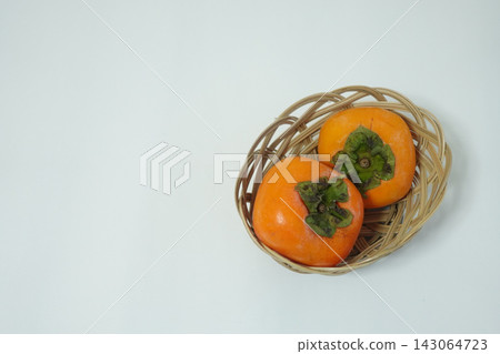 High-resolution stock image of two persimmons in a wicker basket on the right, with a wide margin on the left. High-resolution stock image of two persimmons in a wicker basket on the right, with a wide margin on the left. 143064723