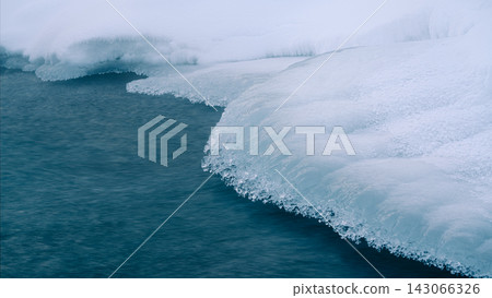 雪下纖細的冰緣和一條藍色的河流 143066326