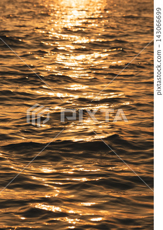 The reflection of the setting sun streaks vertically across the dark surface of the sea. The reflection of the setting sun streaks vertically across the dark surface of the sea. 143066699
