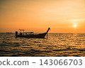 A long-tailed boat on the sea, bathed in the sunset over the Phi Phi Islands. 143066703