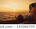 Two people relaxing on a boat at sunset over the Phi Phi Islands. 143066705