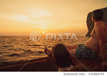 Two people relaxing on a boat at sunset over the Phi Phi Islands. Two people relaxing on a boat at sunset over the Phi Phi Islands. 143066705