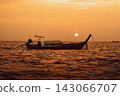 The silhouette of a long-tailed ship floating beneath the round setting sun 143066707