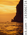 A vertical view of the cliffs with the sunset over the Phi Phi Islands in the background. 143066714
