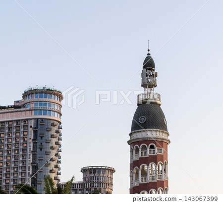 Batumi, Georgia - September 2, 2026: The architectural contrast of the historical style Chacha Tower dome standing in front of the modern Silk Road Sea Towers skyscrapers under a cloudy sky. Travel Batumi, Georgia - September 2, 2026: The architectural contrast of the historical style Chacha Tower dome standing in front of the modern Silk Road Sea Towers skyscrapers under a cloudy sky. Travel 143067399