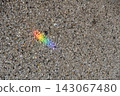 A small rainbow reflected on the gravel ground. 143067480