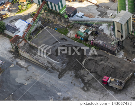 High angle aerial view of an industrial concrete batching plant and aggregate storage bins with a dump truck. High angle aerial view of an industrial concrete batching plant and aggregate storage bins with a dump truck. 143067483