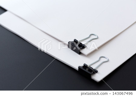 Business documents bound together with a clip, against a black background. Business documents bound together with a clip, against a black background. 143067496