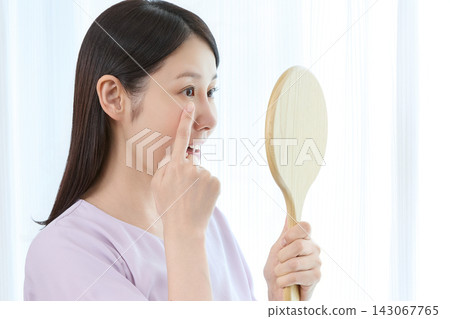 A woman checks the results of her eyelash perm. A woman checks the results of her eyelash perm. 143067765