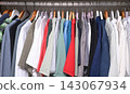view of a organized wardrobe featuring a varied selection of men casual garments suspended on a metal handing rod. 143067934