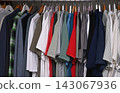 view of a organized wardrobe featuring a varied selection of men casual garments suspended on a metal handing rod. 143067936