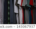 view of a organized wardrobe featuring a varied selection of men casual garments suspended on a metal handing rod. 143067937
