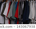 view of a organized wardrobe featuring a varied selection of men casual garments suspended on a metal handing rod. 143067938