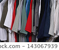 view of a organized wardrobe featuring a varied selection of men casual garments suspended on a metal handing rod. 143067939