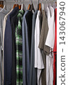 view of a organized wardrobe featuring a varied selection of men casual garments suspended on a metal handing rod. 143067940
