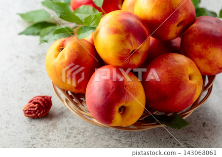 Fresh nectarines with leaves on a kitchen table. Fresh nectarines with leaves on a kitchen table. 143068061