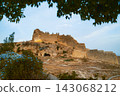 Hilltop fortress ruins framed by tree branches 143068212