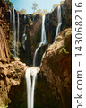 Rushing Waterfall Between Ancient Rock Formations 143068216