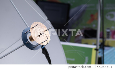 Close view of custom mounted antenna prototype showing circular metal plate, vertical support rods, and cable connection on clean white tabletop, softly lit against blurred workshop background Close view of custom mounted antenna prototype showing circular metal plate, vertical support rods, and cable connection on clean white tabletop, softly lit against blurred workshop background 143068504