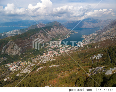 Lovcen Serpentine overlooks Kotor, with bay, city, and mountains spread below. Mountain road winds through rocky slopes, creating dramatic Montenegro panorama for travel and landscape buyers. Lovcen Serpentine overlooks Kotor, with bay, city, and mountains spread below. Mountain road winds through rocky slopes, creating dramatic Montenegro panorama for travel and landscape buyers. 143068558