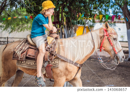 Child enjoys western horseback riding during a farm visit. Outdoor recreation and family farm leisure. Child enjoys western horseback riding during a farm visit. Outdoor recreation and family farm leisure. 143068657