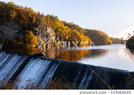 Autumn Forest Reflected Across Quiet Lake. Peaceful autumn nature concept symbolizing seasonal transformation harmony and beauty of untouched landscapes Autumn Forest Reflected Across Quiet Lake. Peaceful autumn nature concept symbolizing seasonal transformation harmony and beauty of untouched landscapes 143068699