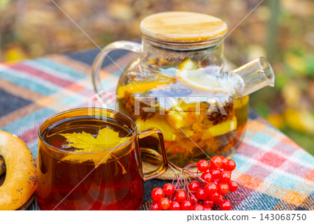 Autumn Tea Cup With Floating Maple Leaf at Outdoor Picnic Autumn Tea Cup With Floating Maple Leaf at Outdoor Picnic 143068750