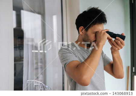 Portrait of man observing through monocular, exploring distance and focusing on details, utilizing optical equipment for research, discovery and detailed vision. Concept of discovering, exploring. Portrait of man observing through monocular, exploring distance and focusing on details, utilizing optical equipment for research, discovery and detailed vision. Concept of discovering, exploring. 143068913